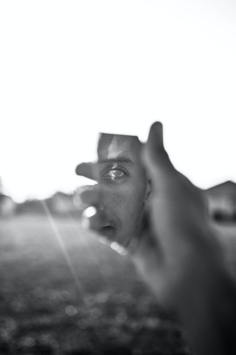 A person holding up a mirror fragment that's reflecting back at their eye.